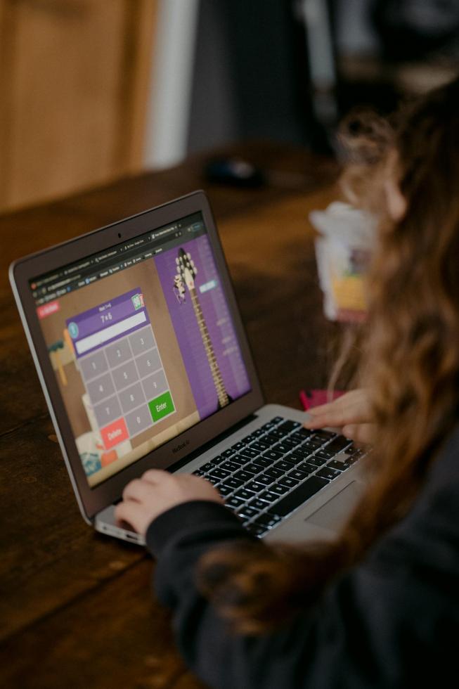 young girl playing an academic game on a laptop