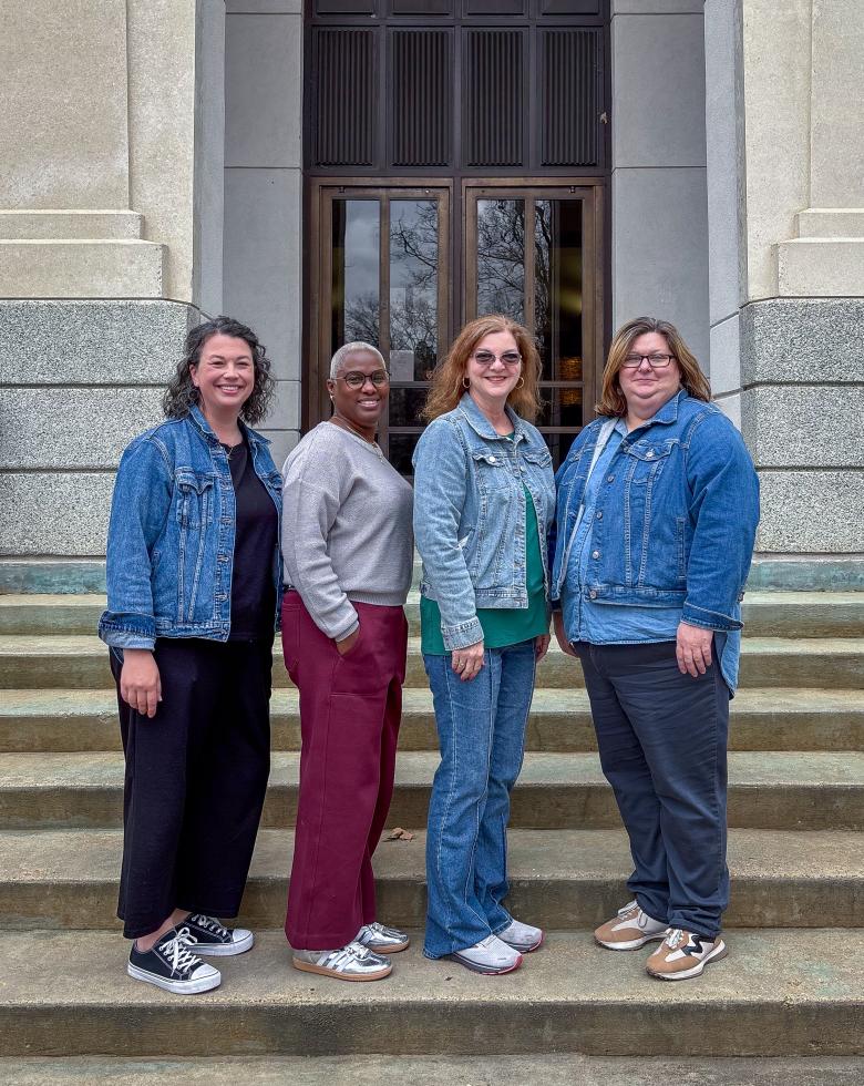 Four female counselors stand on marble steps for a group picture