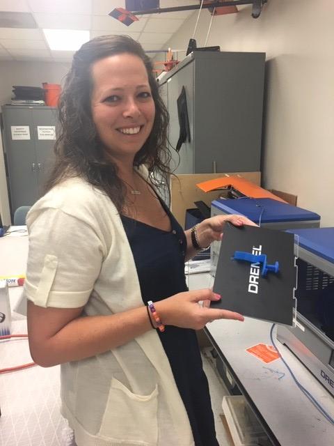 Teacher Katie Thompson removes her completed seat design from the 3D printer.