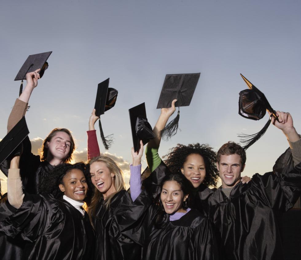 A group of graduates throw their caps in their air. 