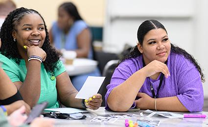 Two women in a Making Schools Work Conference session listening and smiling