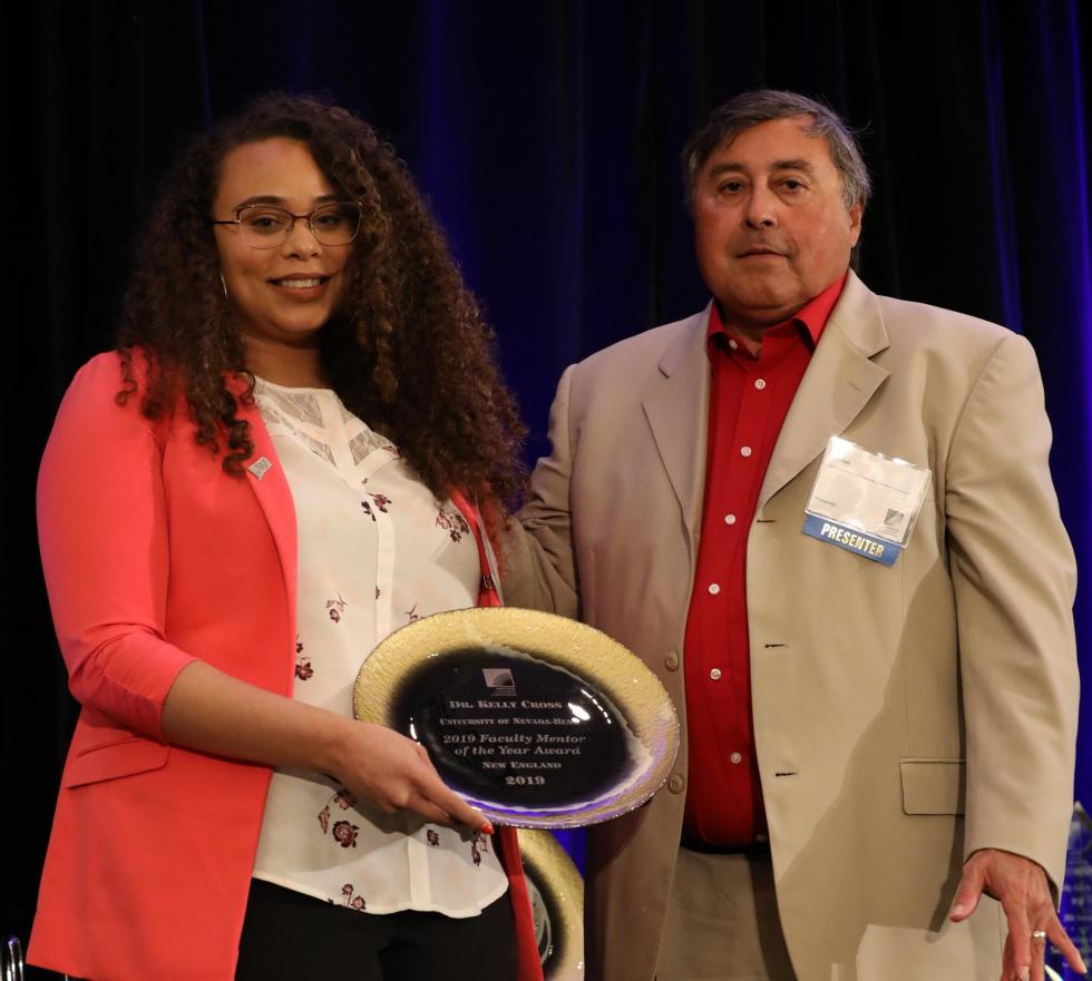 Doctoral student Stephany Santos accepts the award from Dr. Ken Pepion on behalf of Dr. Cross.