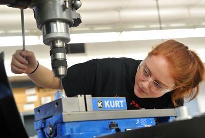 Photo of a female CTE student operating a drill press.