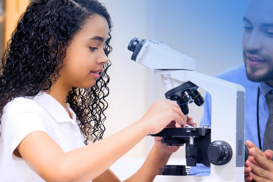 A teacher helping a child use a microscope.