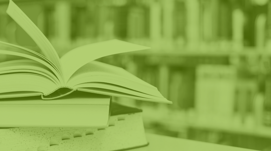 A stack of library books sitting on a table. The top book is open.