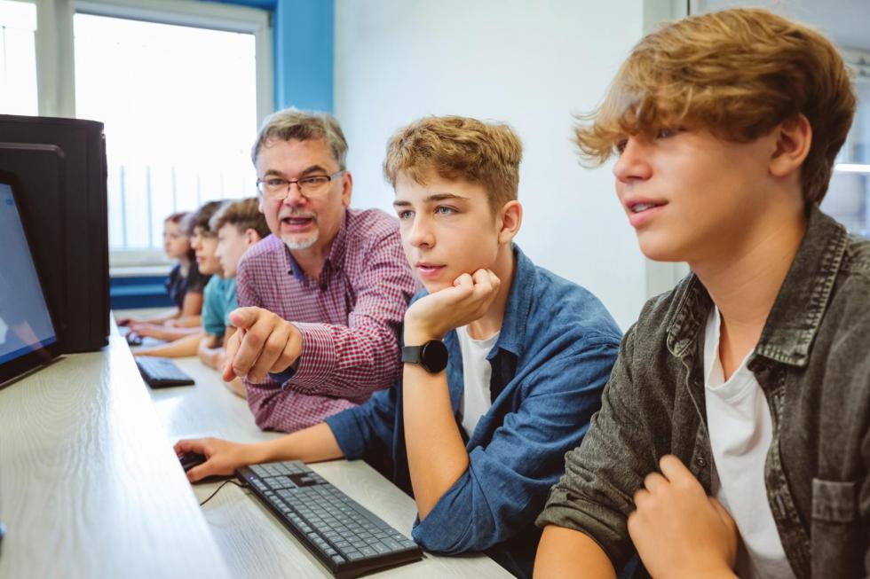 teacher and two students looking at computer