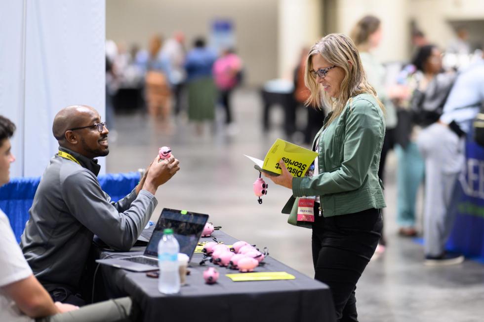 An attendee at the 2025 conference meets an author at a book signing