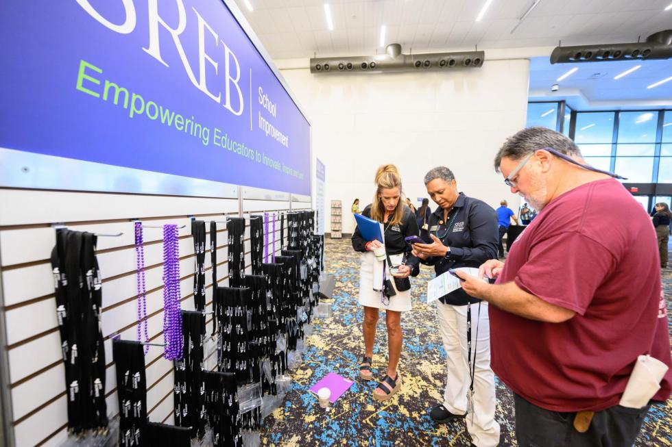 SREB team and a conference attendee look at the app at the 2025 conference