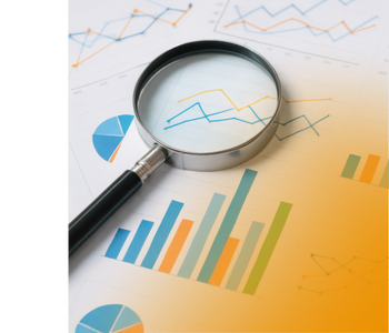 A magnifying glass on top of various charts and graphs.